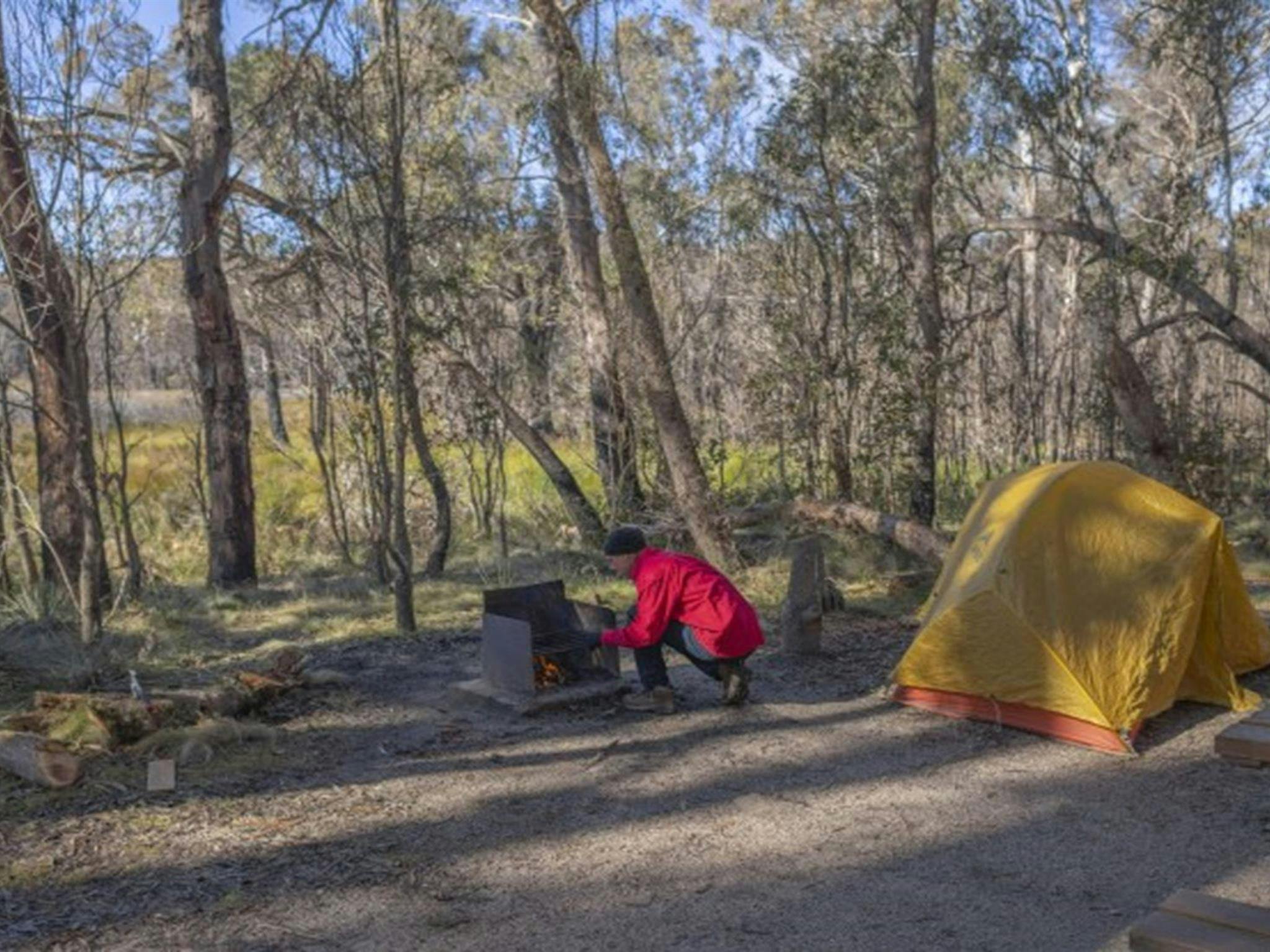 A man tends to the wood barbecue next to his tent at Barokee campground in Cathedral Rock National