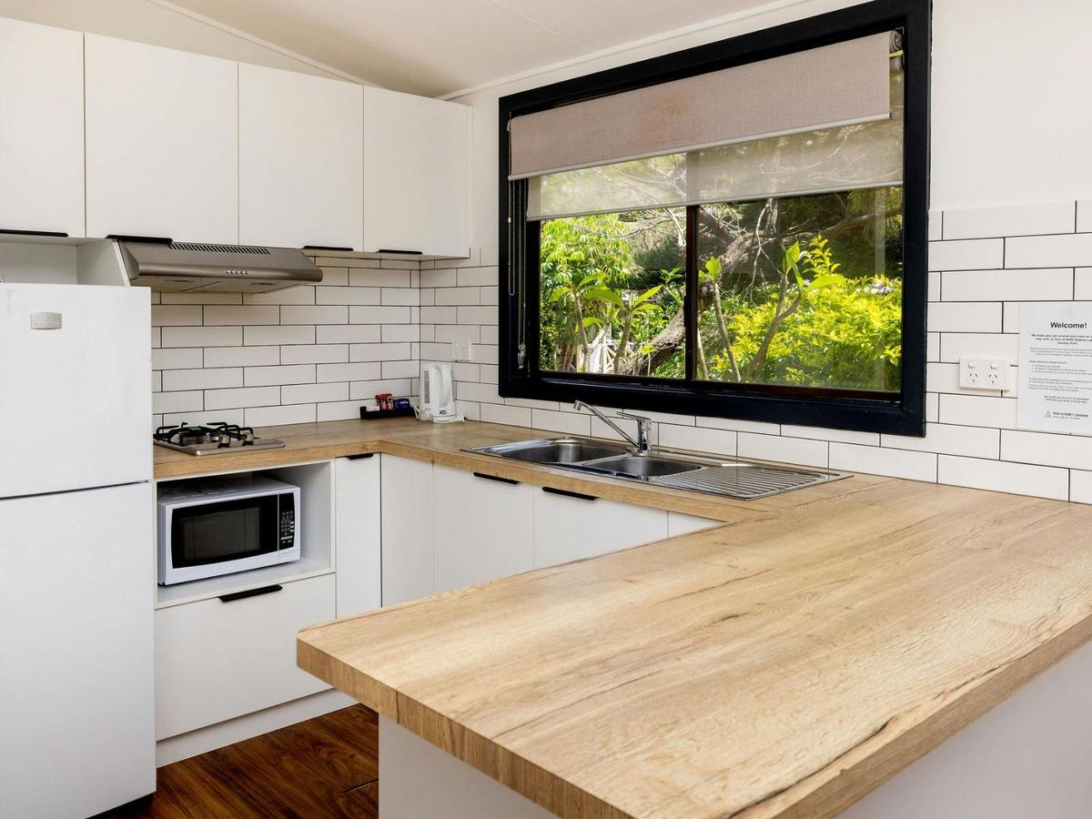Kitchen with benches, fridge, microwave and cabinetry