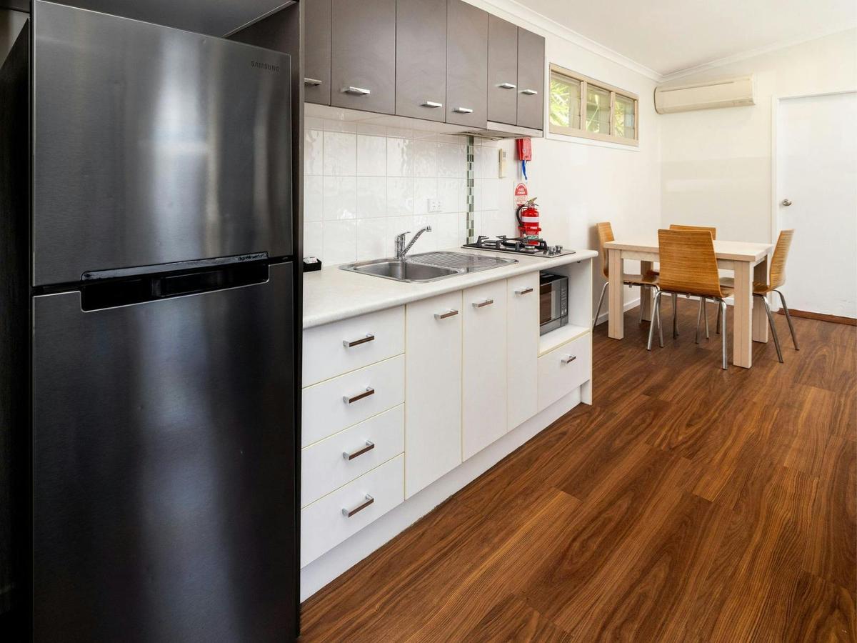 Kitchen with fridge, bench, sink, microwave and dining table with seating for 4