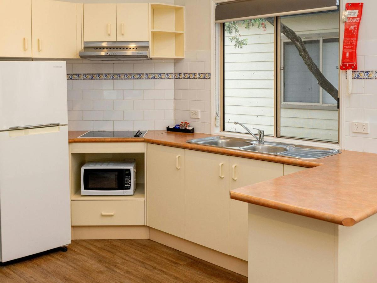 Kitchen with fridge, benches, microwave and cabinetry