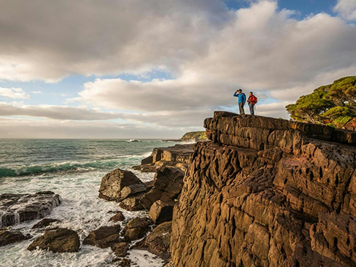 Bushwalkers on cliffside, Bittangabee campground, Beowa National Park. Photo: John Spencer/OEH