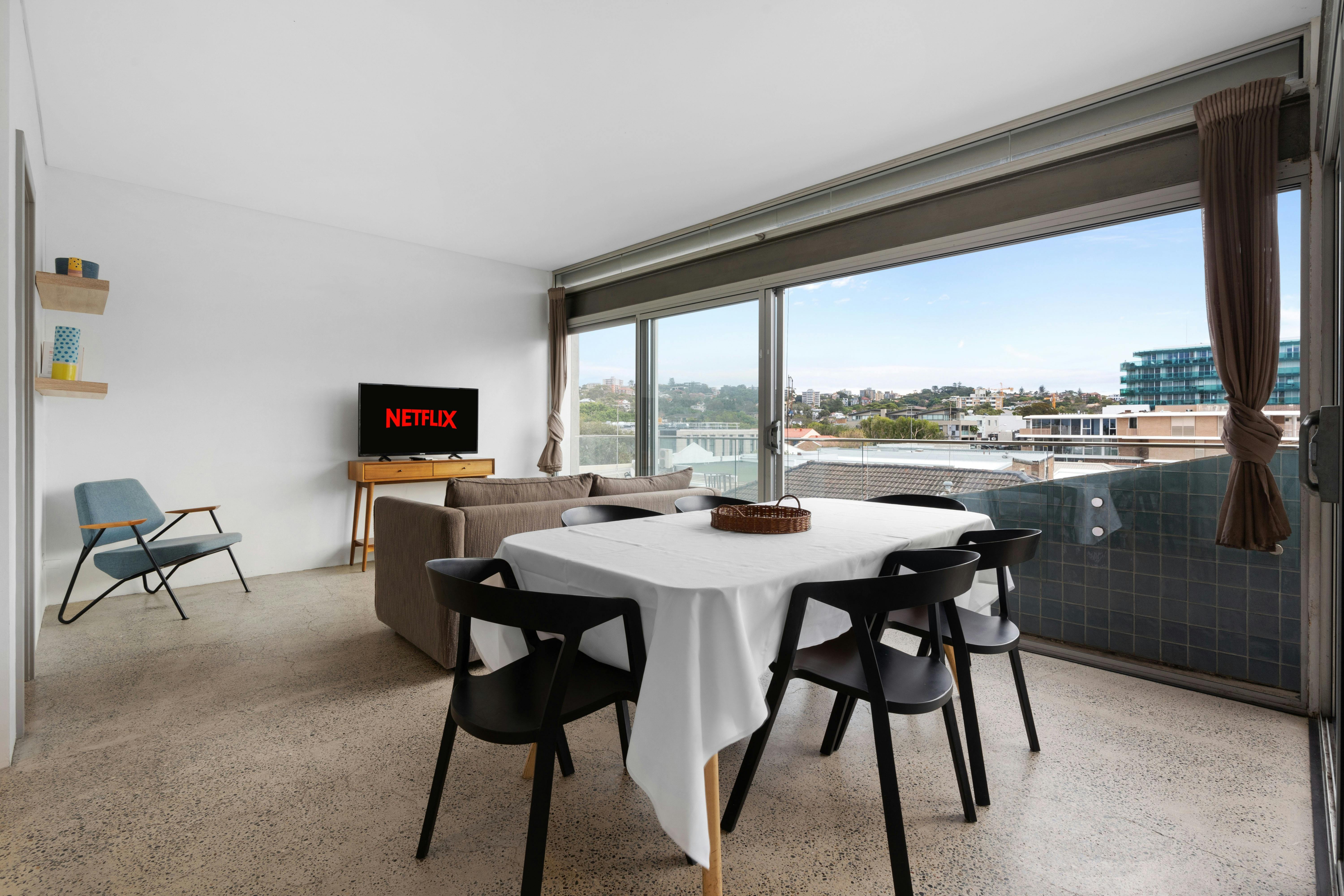 Stunning city views from a modern apartment with a cozy living space and balcony seating.
