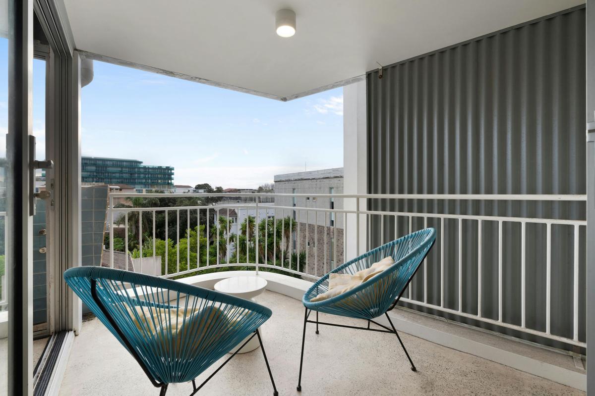 Stunning city views from a modern apartment with a cozy living space and balcony seating.