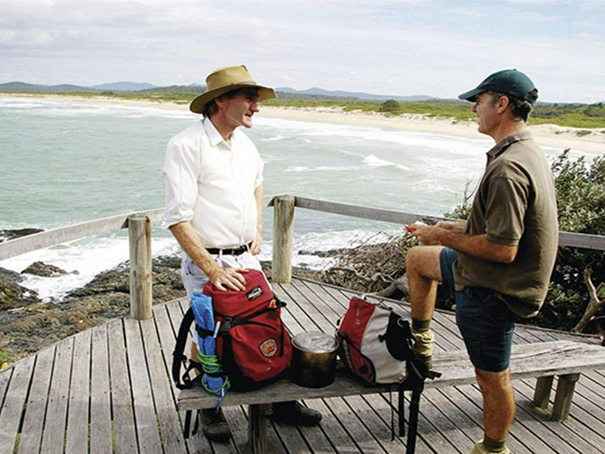 Bushwalkers on wooden deck on a coastal walk near Boorkoom campground in Yuraygir National Park.