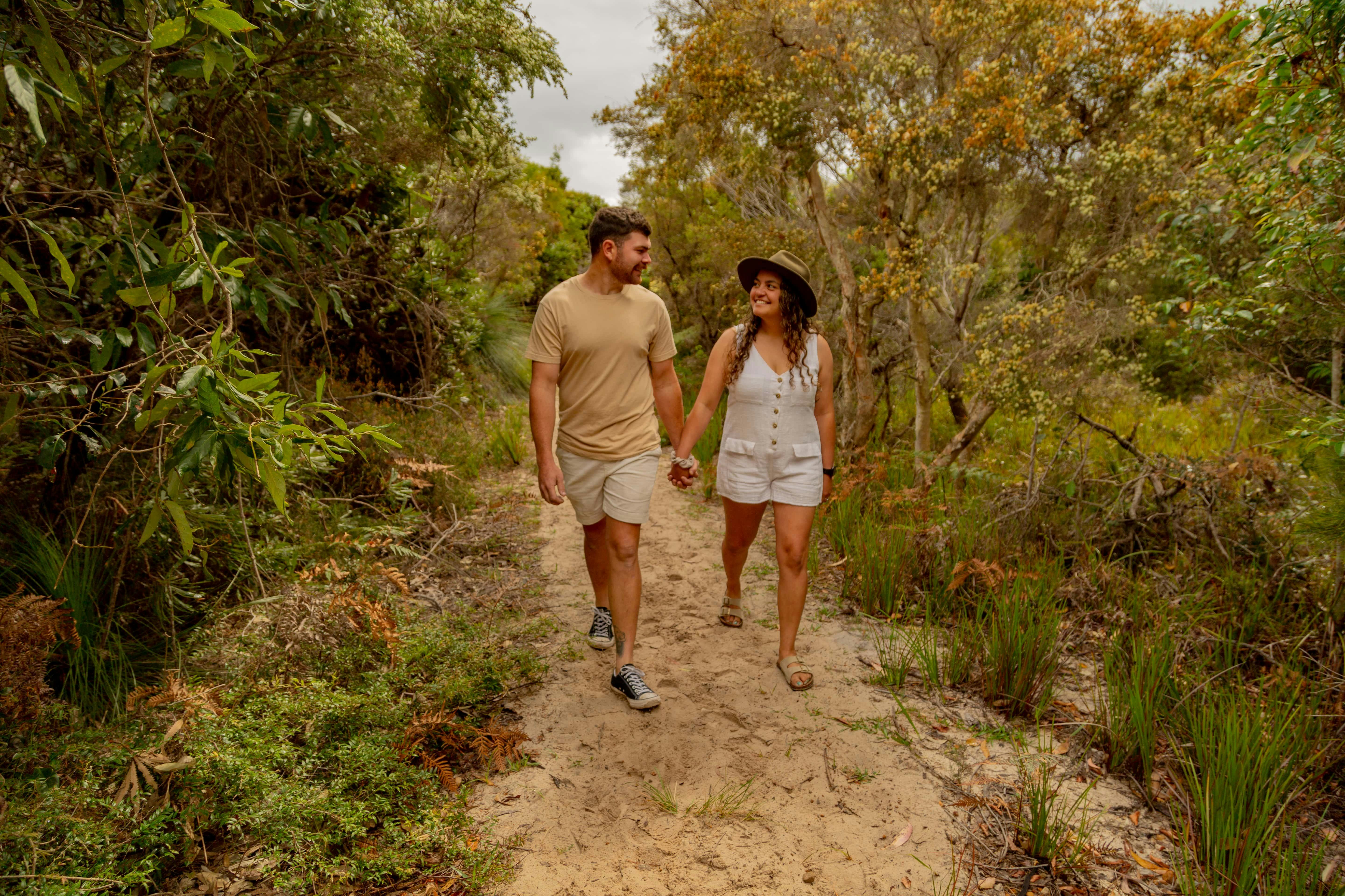 A lady and a man walking through the bush on a path