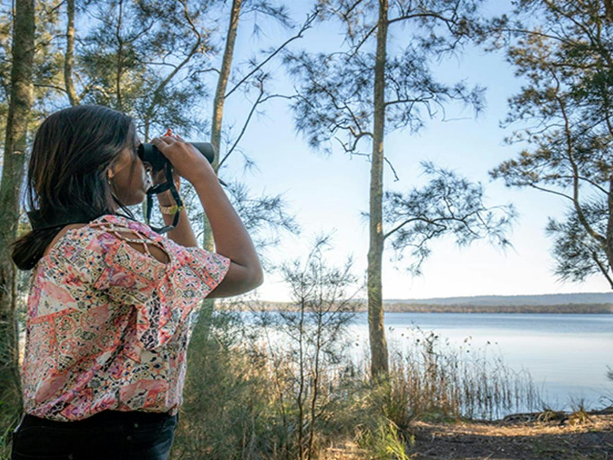 Camper looking out over Boolambayte Lake, Bungarie Bay campground. Photo: John Spencer/OEH