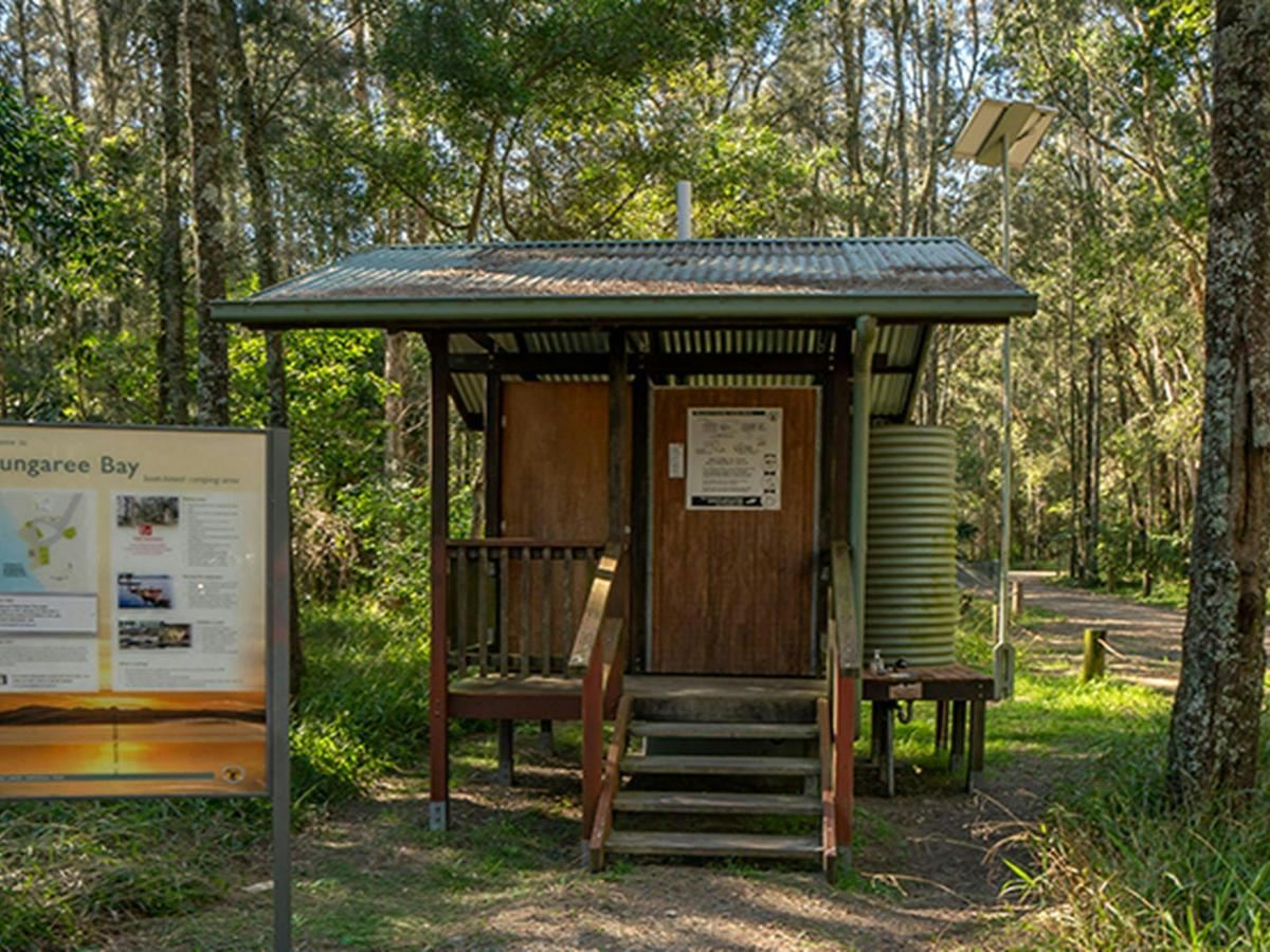 Lady reviewing the sign at Bungarie Bay campground. Photo: John Spencer/OEH