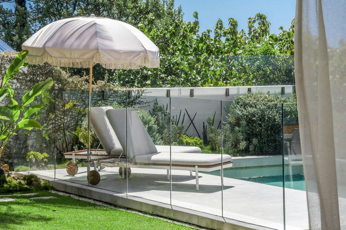 Relaxing pool area with a pool umbrella, surrounded by lounge chairs and lush greenery