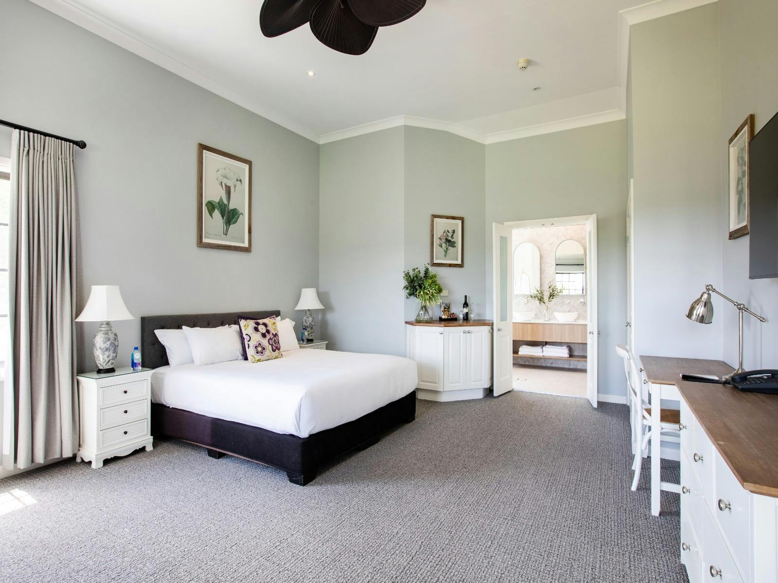 A large bedroom showcasing a bed, a dresser, and a ceiling fan, designed for relaxation and comfort