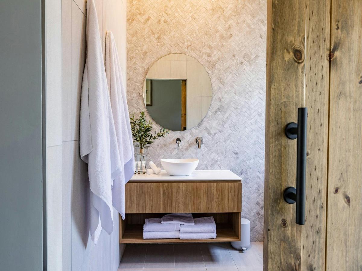 A bathroom featuring a wooden door and a modern sink, showcasing a clean and functional design.