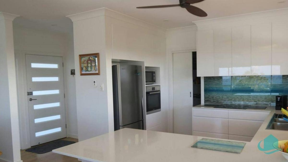 Gourmet kitchen with ceiling fans and unique splashback