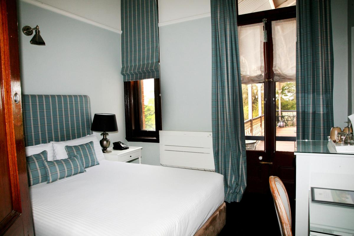 A king bed next to some open blinds showing a view of the deck