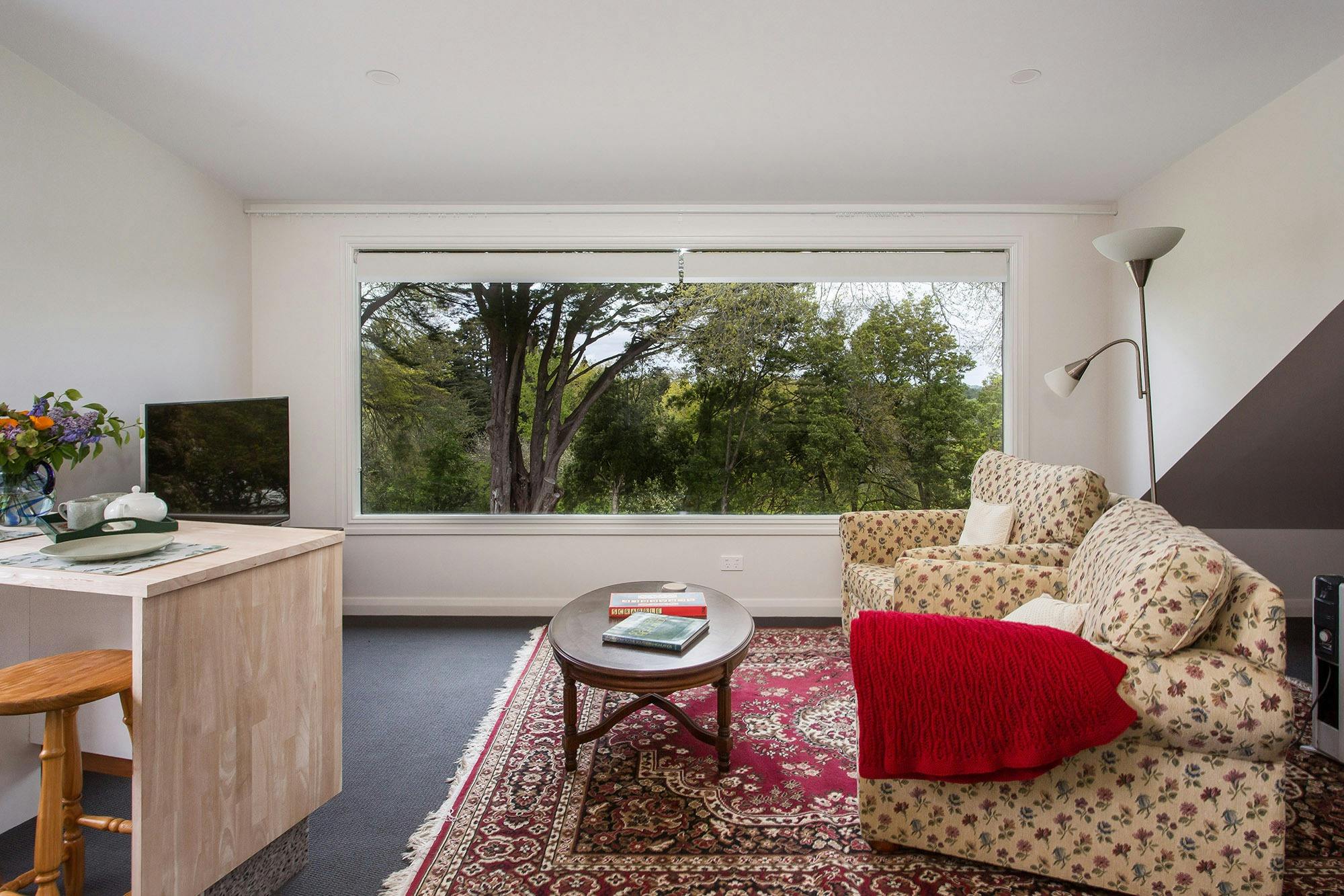 Comfortable lounge area and huge picture window  looking out to tree tops