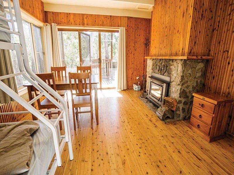 Interior of Dickson cabin with beds, dining table and fireplace. Photo: Simone Cottrell/OEH