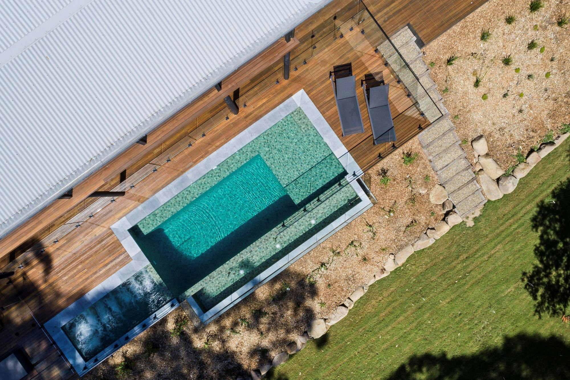 Sun-soaked expansive deck surrounding pool and spa with sun lounges and outdoor living