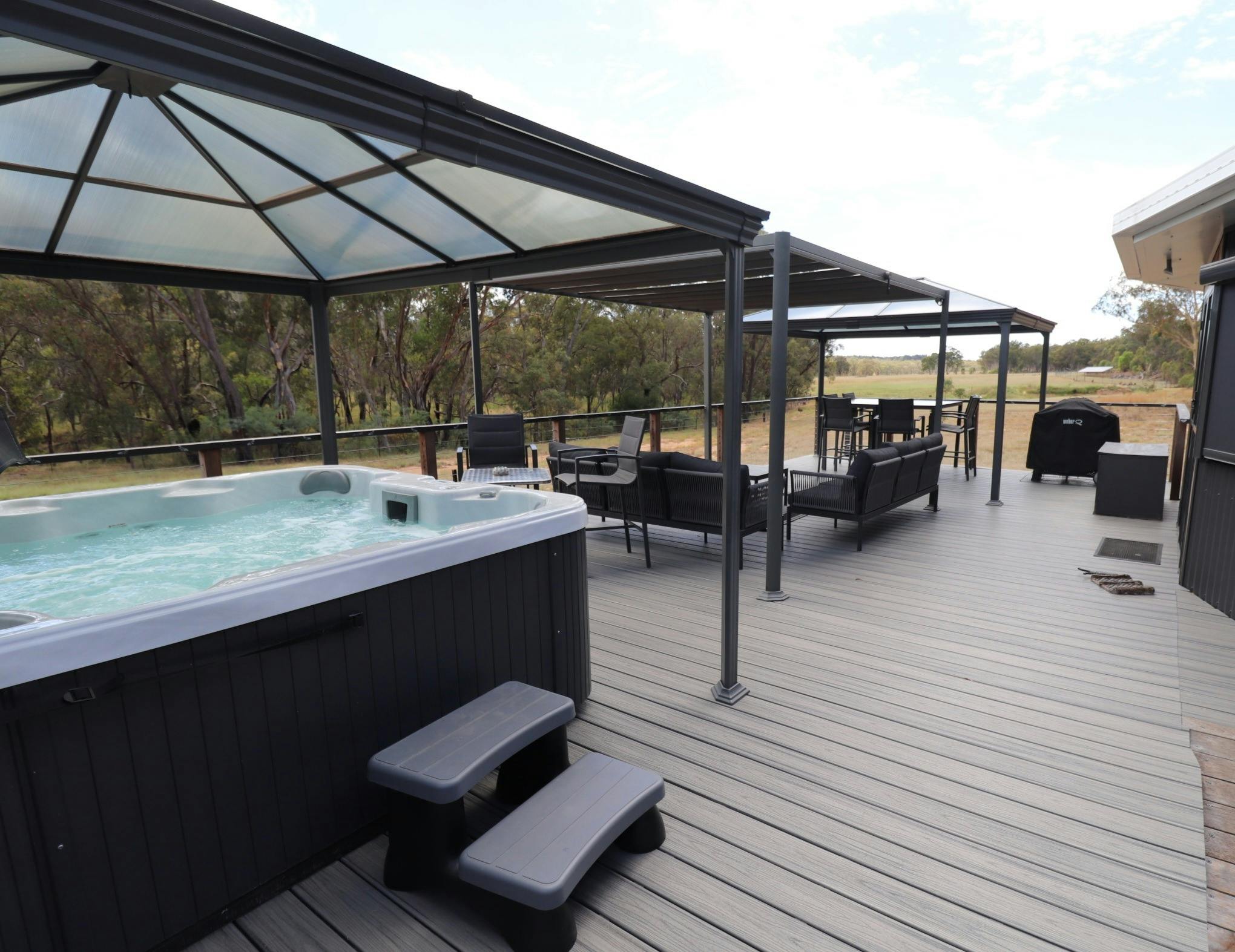 The 3 bedroom Banksia Lodge deck spa and outdoor living area with the emus entertaining guests