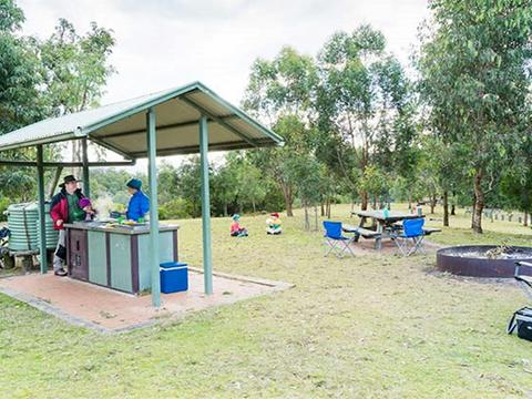 A family cooks on undercover gas barbecues at Dunphys campground, Blue Mountains National Park.
