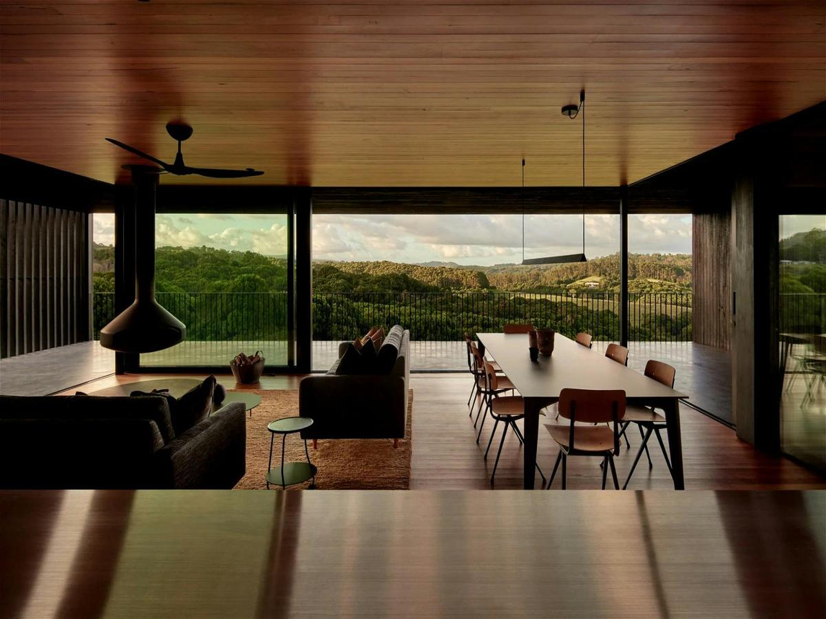 Light-filled yet chic moody interior, with large windows, open plan living, and panoramic views