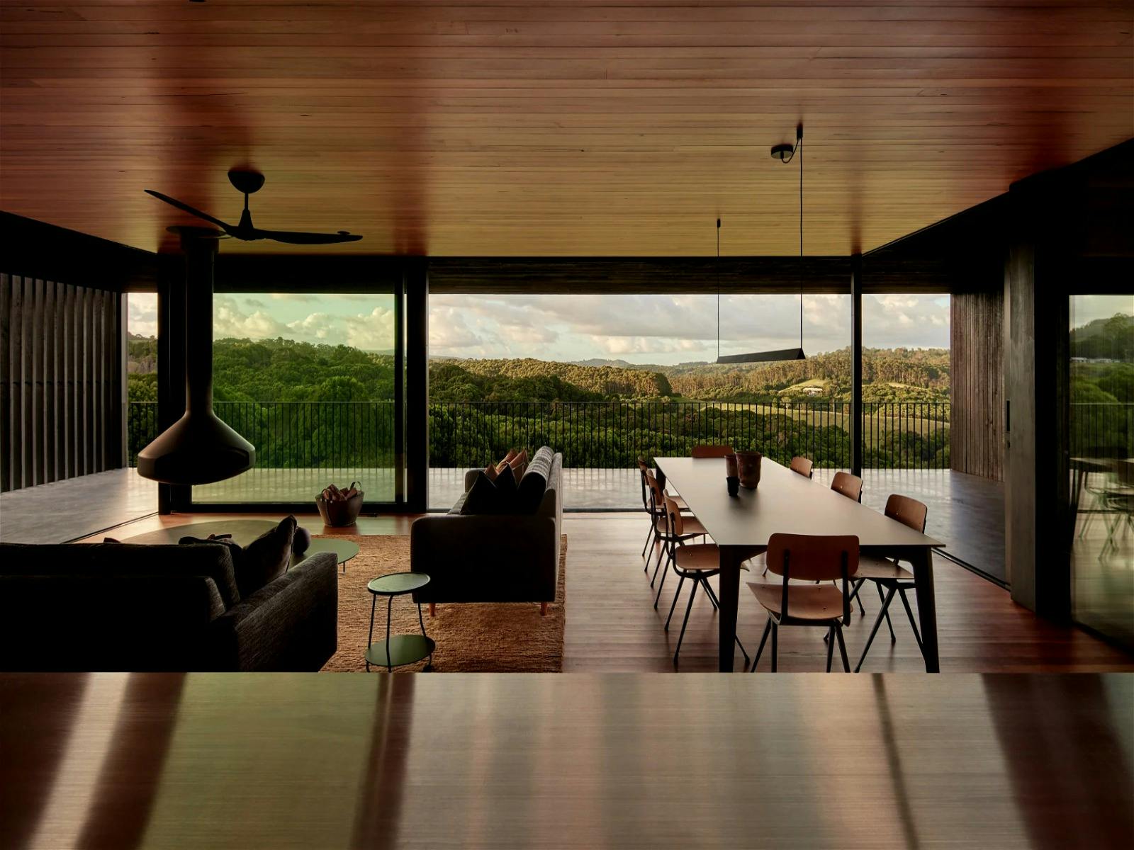 Light-filled yet chic moody interior, with large windows, open plan living, and panoramic views