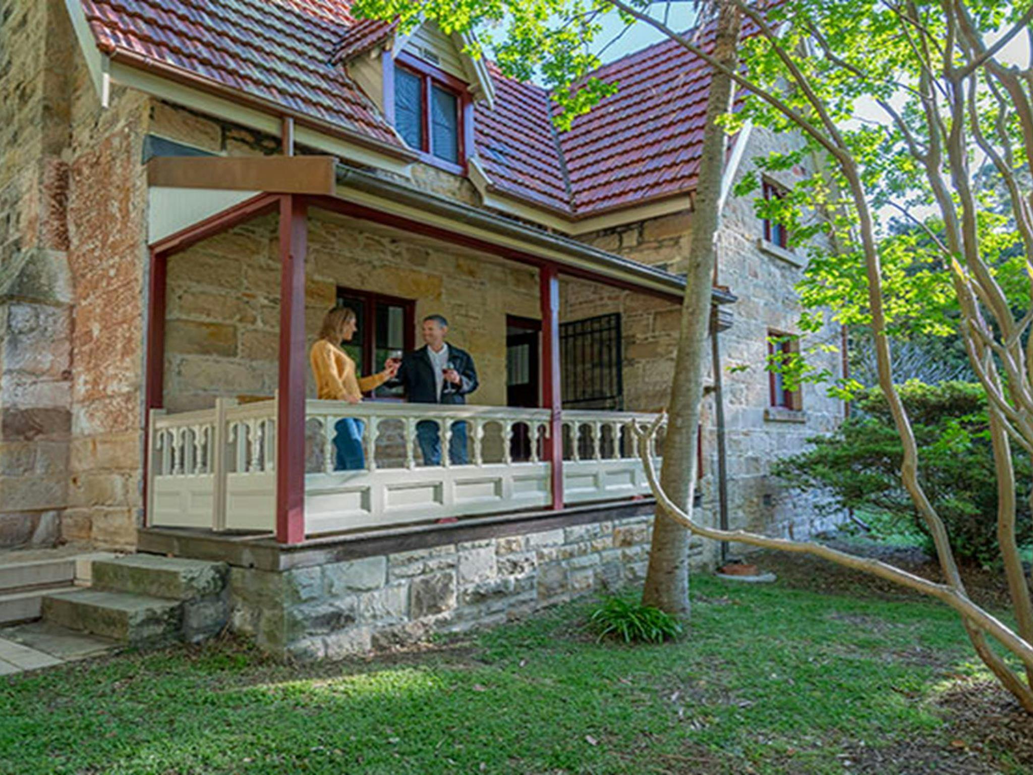 Two people on the verandah of Gardeners Cottage in Sydney Harbour National Park. Photo: John