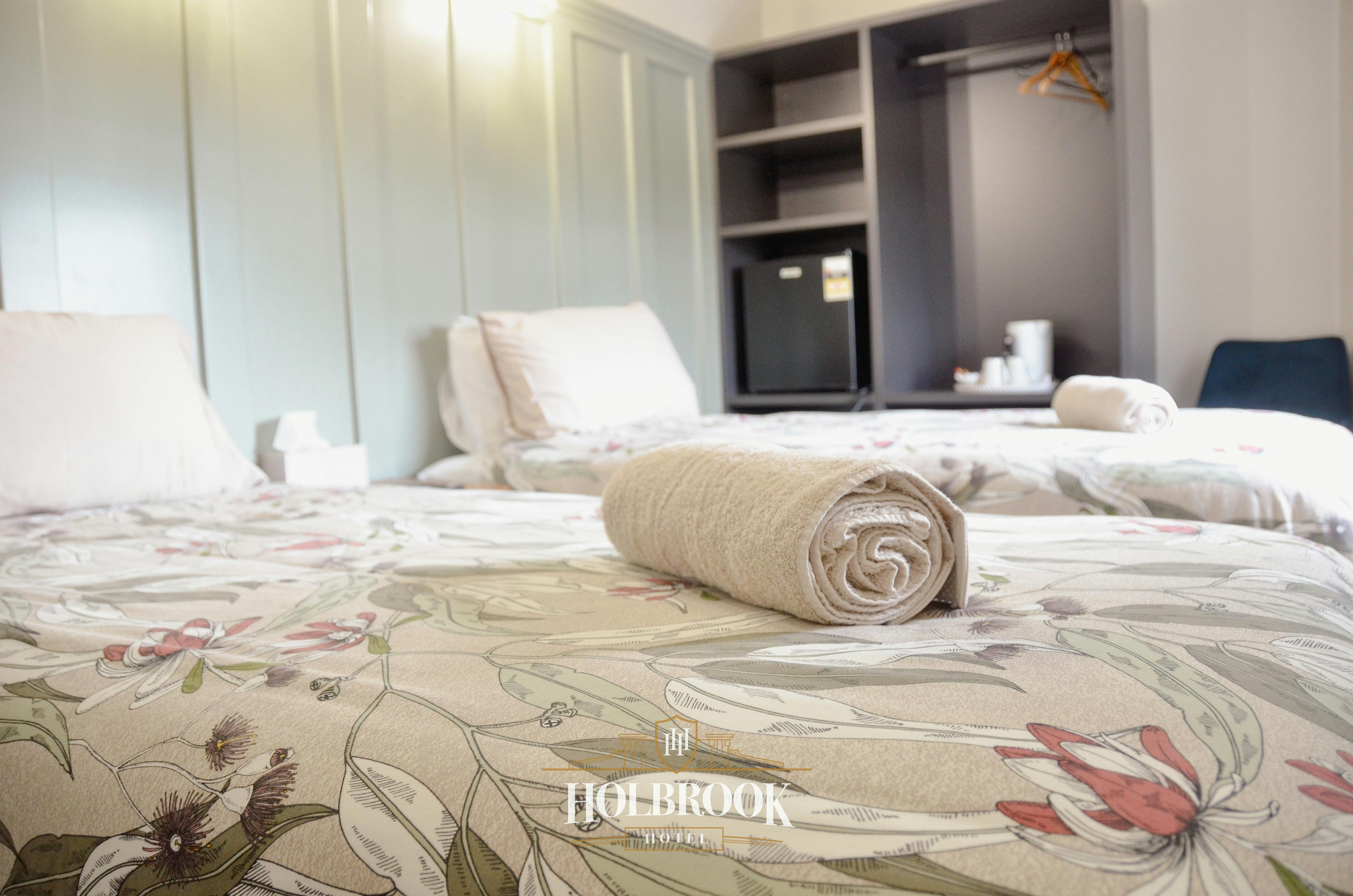 Twin beds with floral sheets and a light green headboard