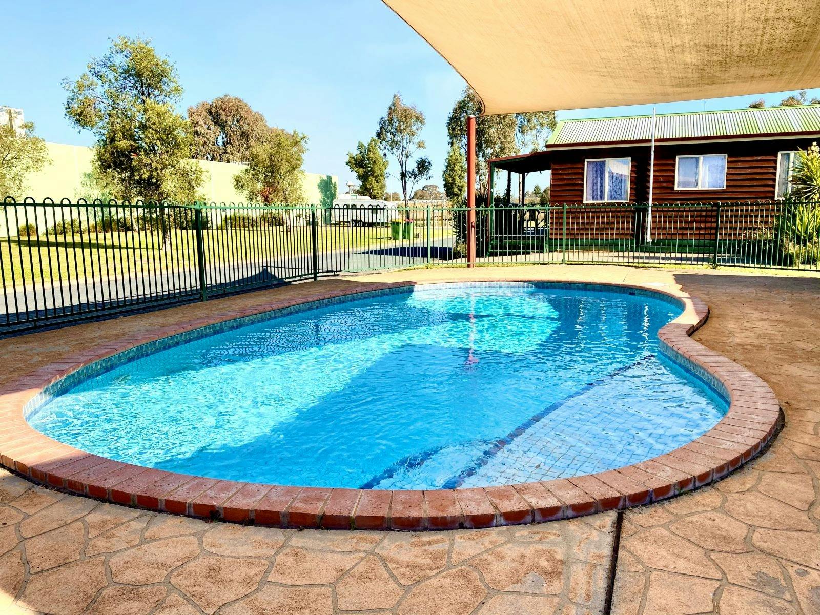 Round shaped pool with bricks around it and a shade cover
