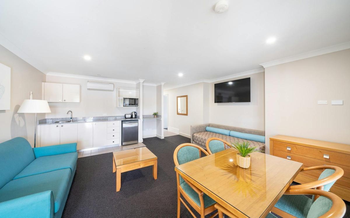 Relax in our stylish lounge room featuring a fully equipped kitchen and a dining area with chic blue