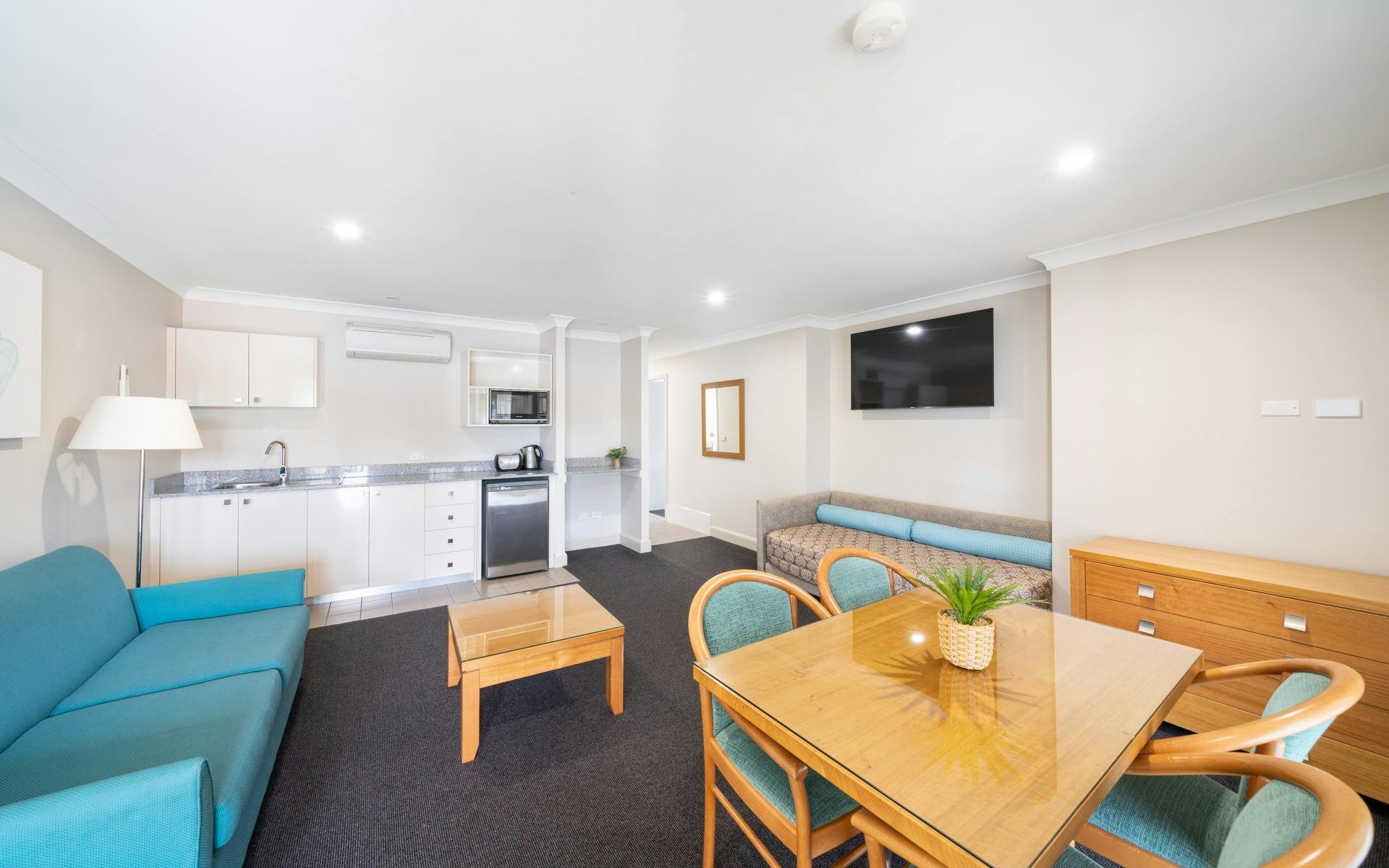 Relax in our stylish lounge room featuring a fully equipped kitchen and a dining area with chic blue