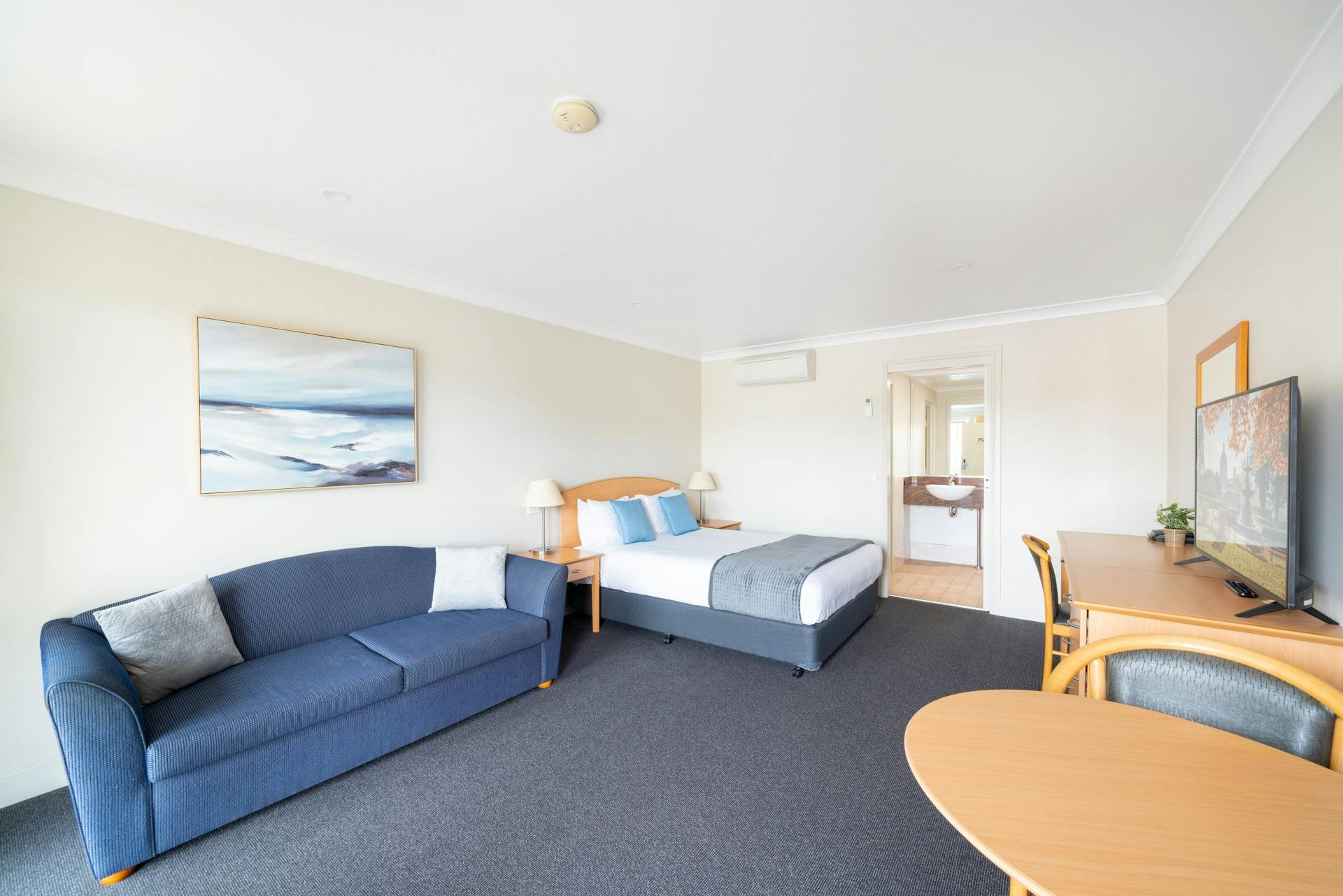 Relax in comfort and style in our spacious hotel room featuring a comfortable bed and a cozy lounge