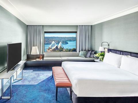 Hotel room with bed and banquette overlooking Sydney Opera House