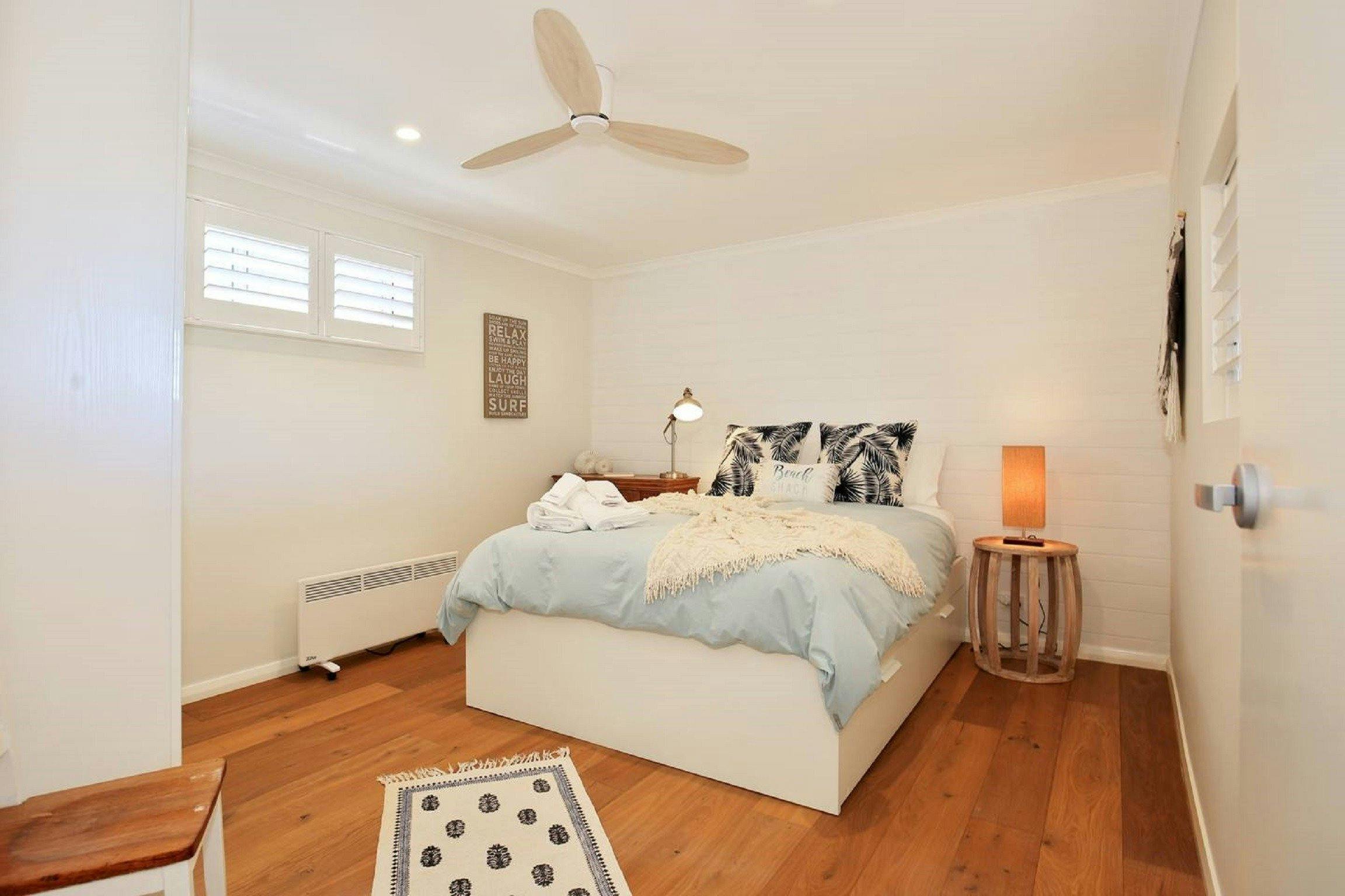 Stunning queen bedroom with ceiling fan adjacent to bathroom.