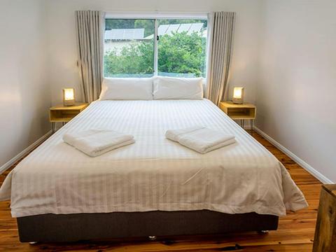 Judges House bedroom with queen bed and back wall window, Murramarang National Park. Photo: John