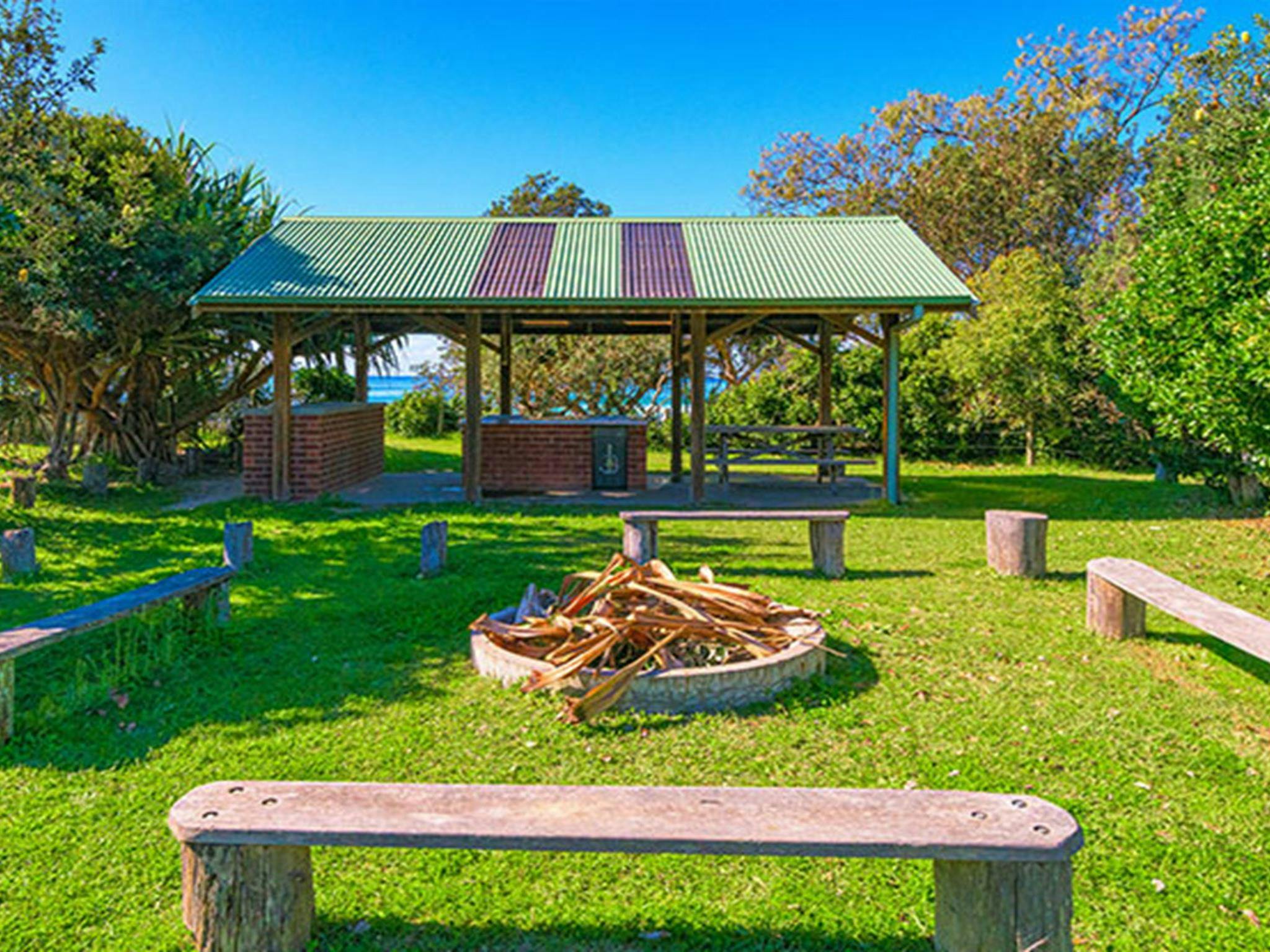 An area with benches and a firepit, perfect for groups at Illaroo group camping area in Yuraygir