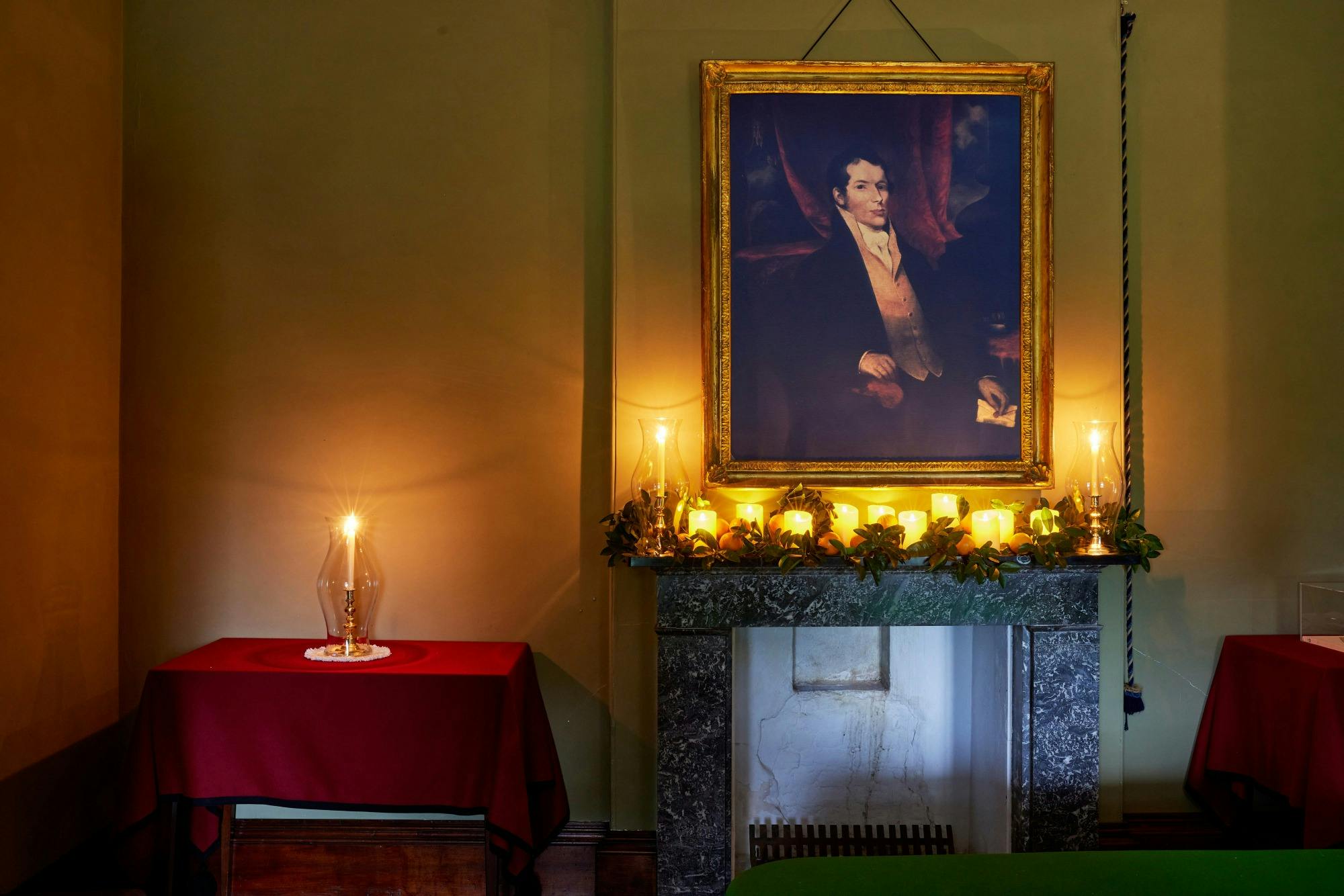 Historic living room mantle lit with candles and a portrait