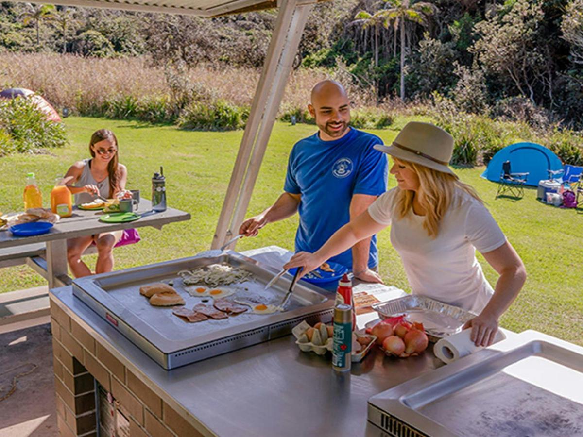 Campers under the barbecue shelter cooking and enjoying breakfast, Bouddi National Park. Photo: John