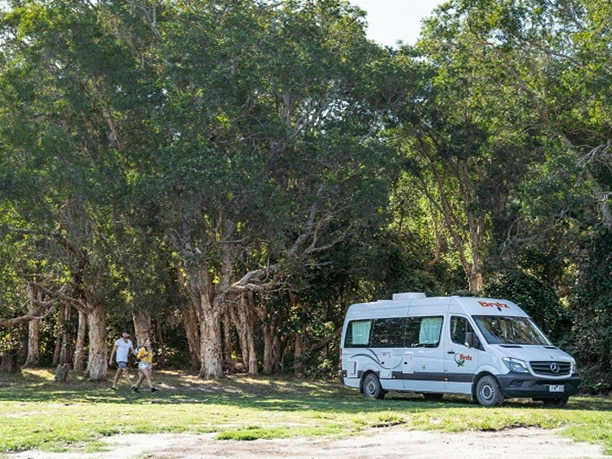 A couple walking across Kylies Beach campground to their campervan, Crowdy Bay National Park. Photo: