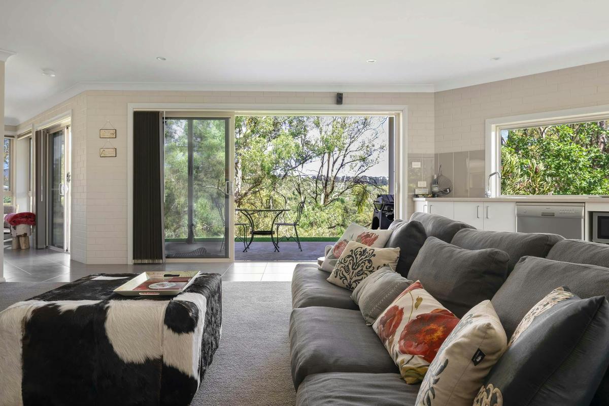 Lounge area showing kitchen behind and large windows to the patio and garden