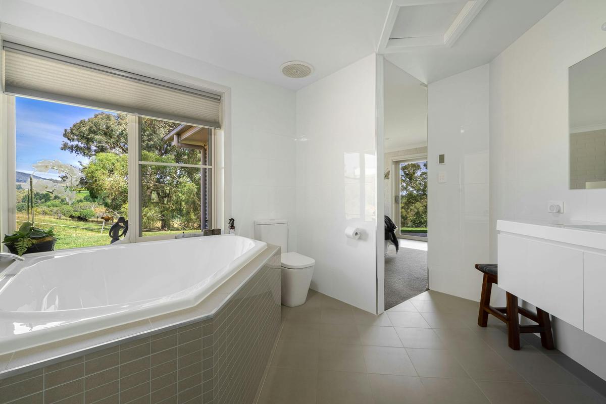 Large bathroom with triangular bath and garden view from window over bath
