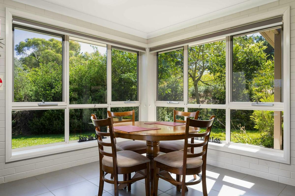 Dining area with 4 seats at table with two big picture windows looking into the garden