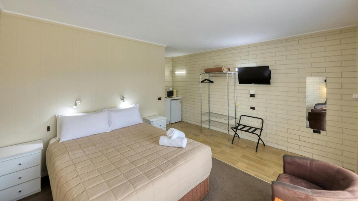 Queen Room overlooking the queen sized bed, wall mounted tv and storage area.