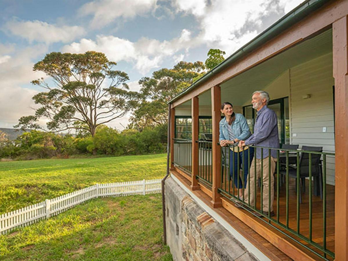 Two people standing on the back verandah of Middle Head Officers Quarters in Sydney Harbour National