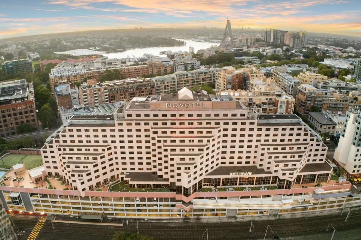 Aerial hero view of Novotel Sydney on Darling Harbour at sunset, showcasing the hotel’s prime waterf