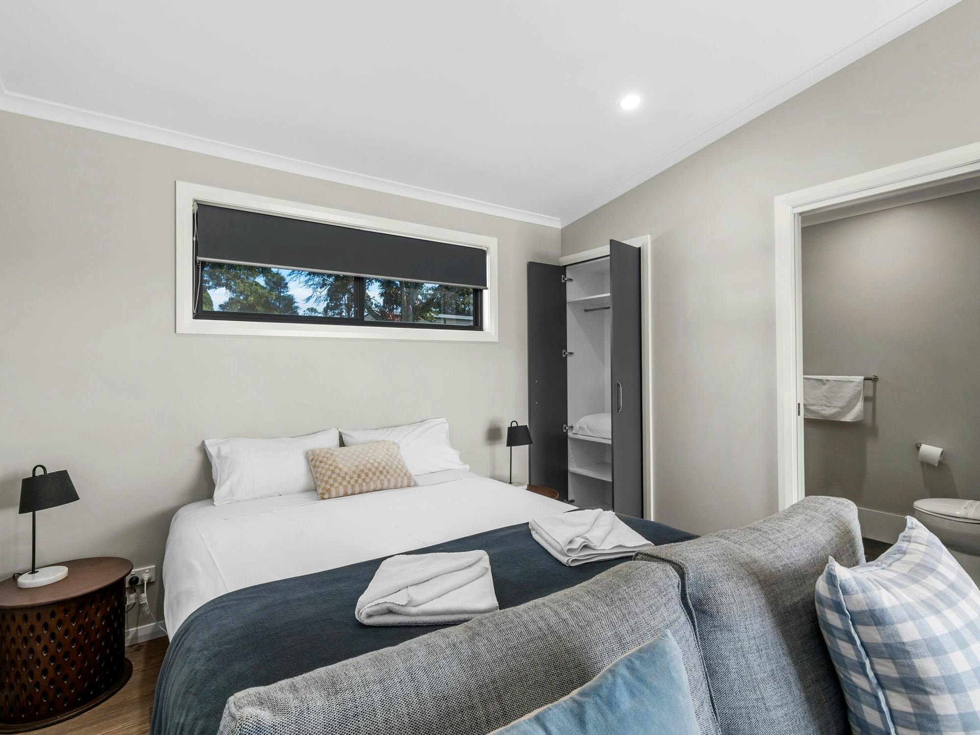 Modern cabin bedroom featuring a queen-sized bed with white linens, bedside tables with lamps.