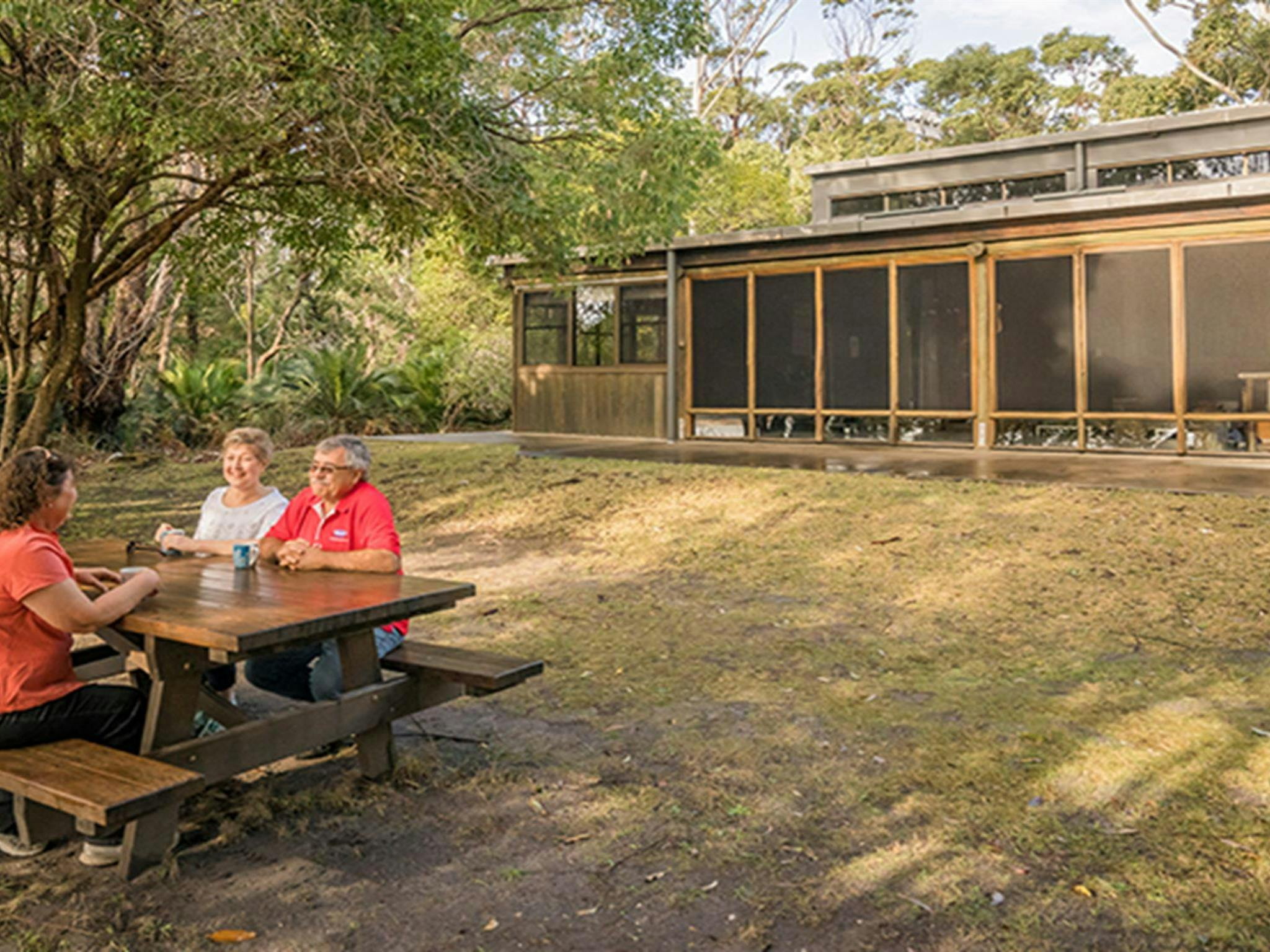 Visitors at a picnic table outside Myer House in Mimosa Rocks National Park. Photo: OEH/John Spencer