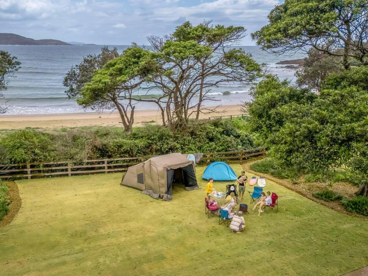 A family camping on a grassy site by the beach on the NSW north coast at Point Plomer campground in
