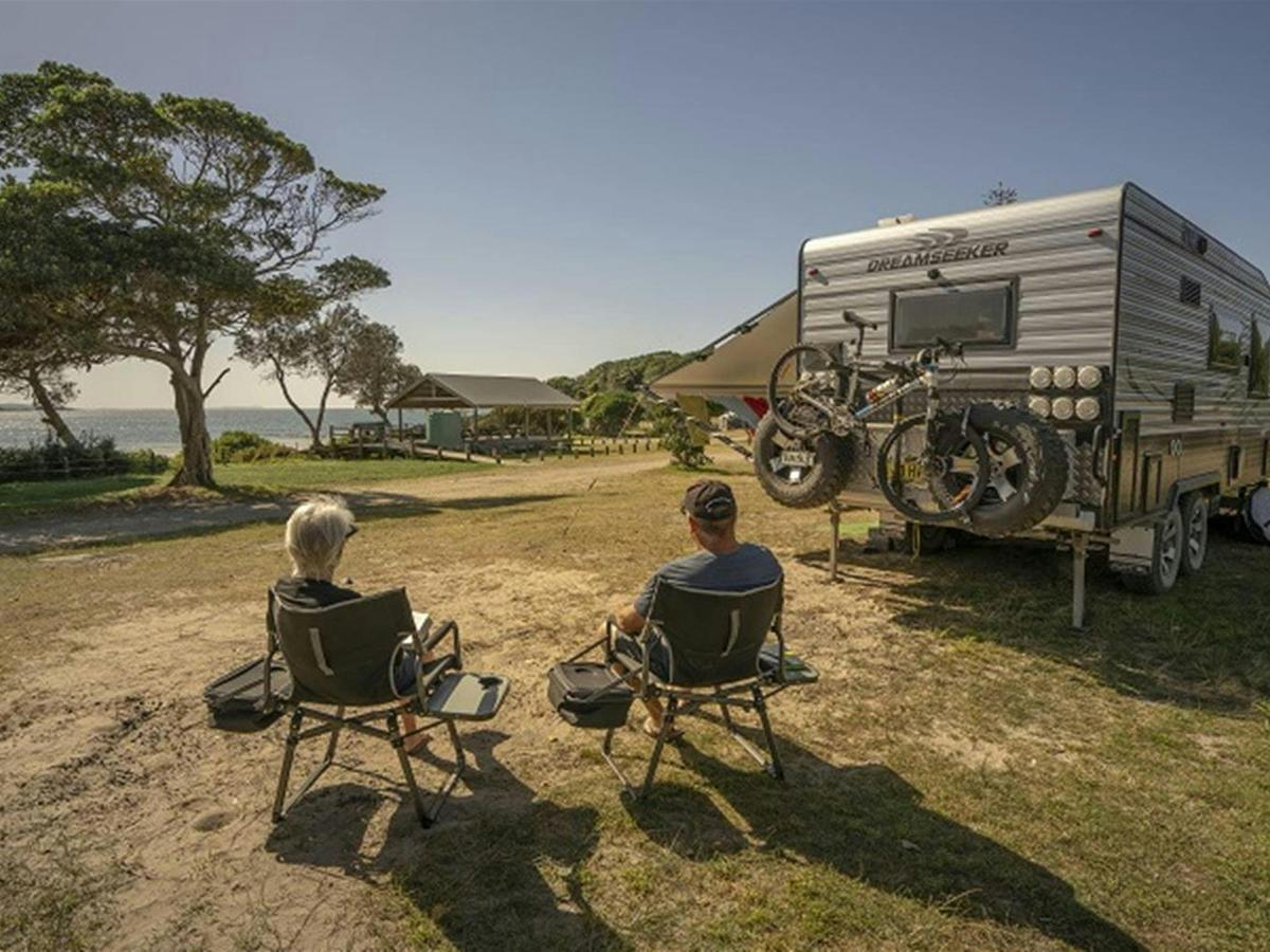 2 people sitting down beside their campervan looking out at the ocean at Point Plomer campground,