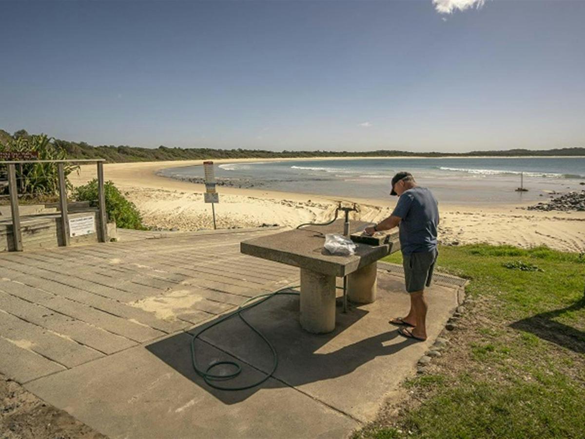 A fisherman cleaning his fish on a bench nearby the beach at Point Plomer campground, Limeburners