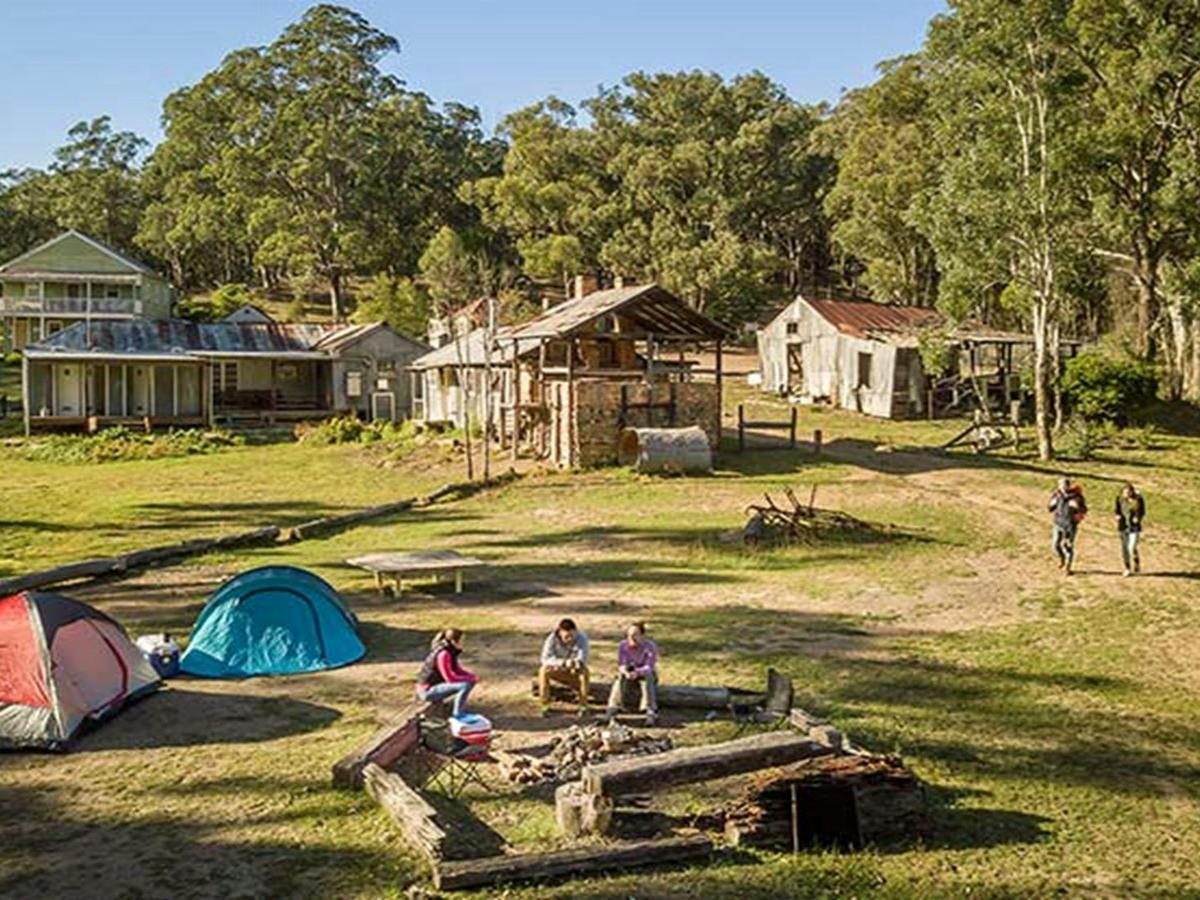 Campers sitting around the fire pit near their tents at Private Town campground in Yerranderie