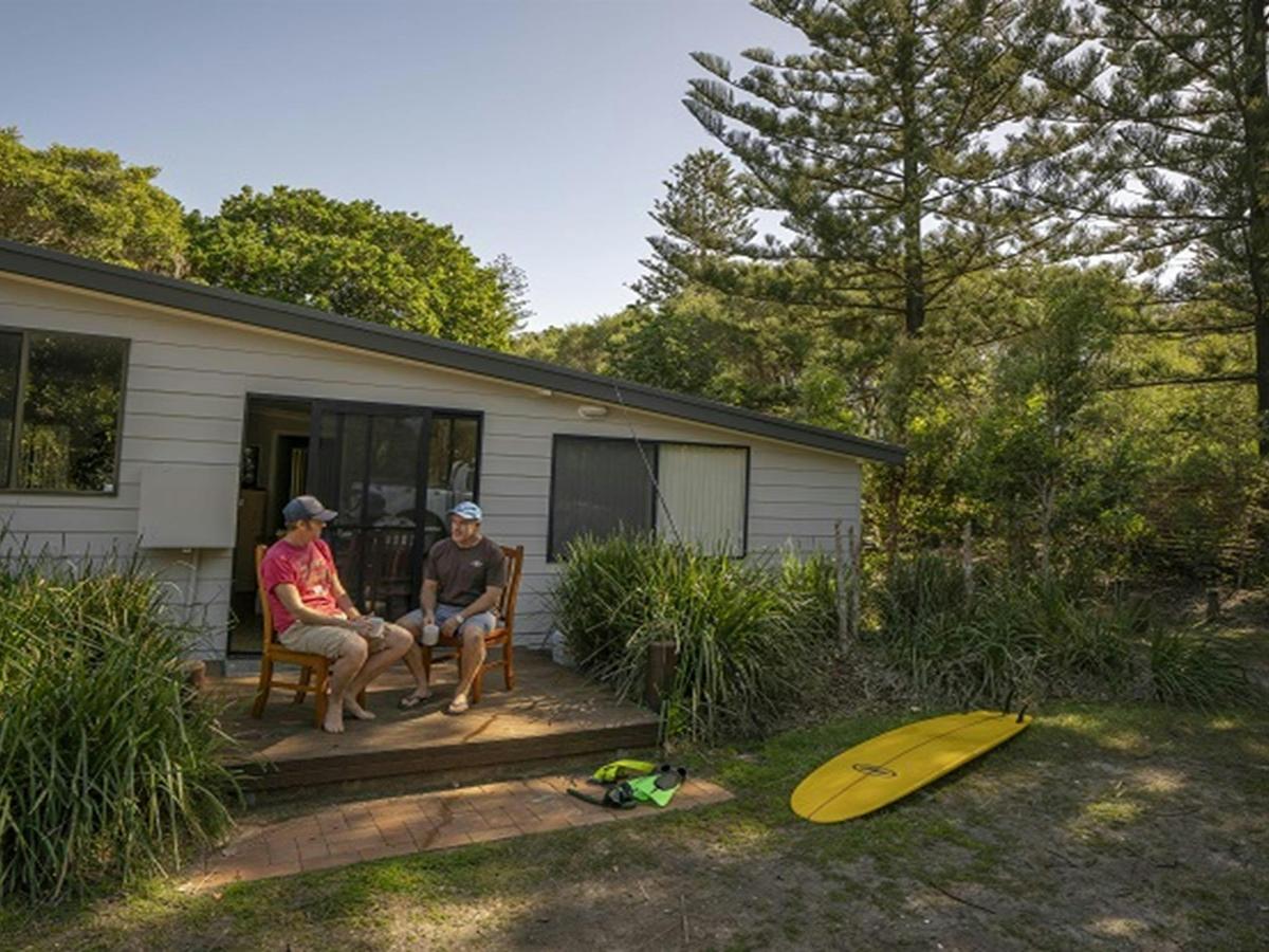 2 people sitting outside on the deck drinking a cup of coffee at Plomer Beach House, Limeburners