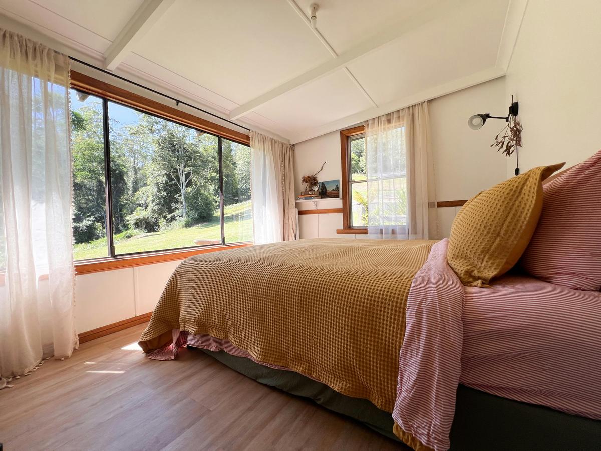 The bedroom faces the forest with large windows and a king bed
